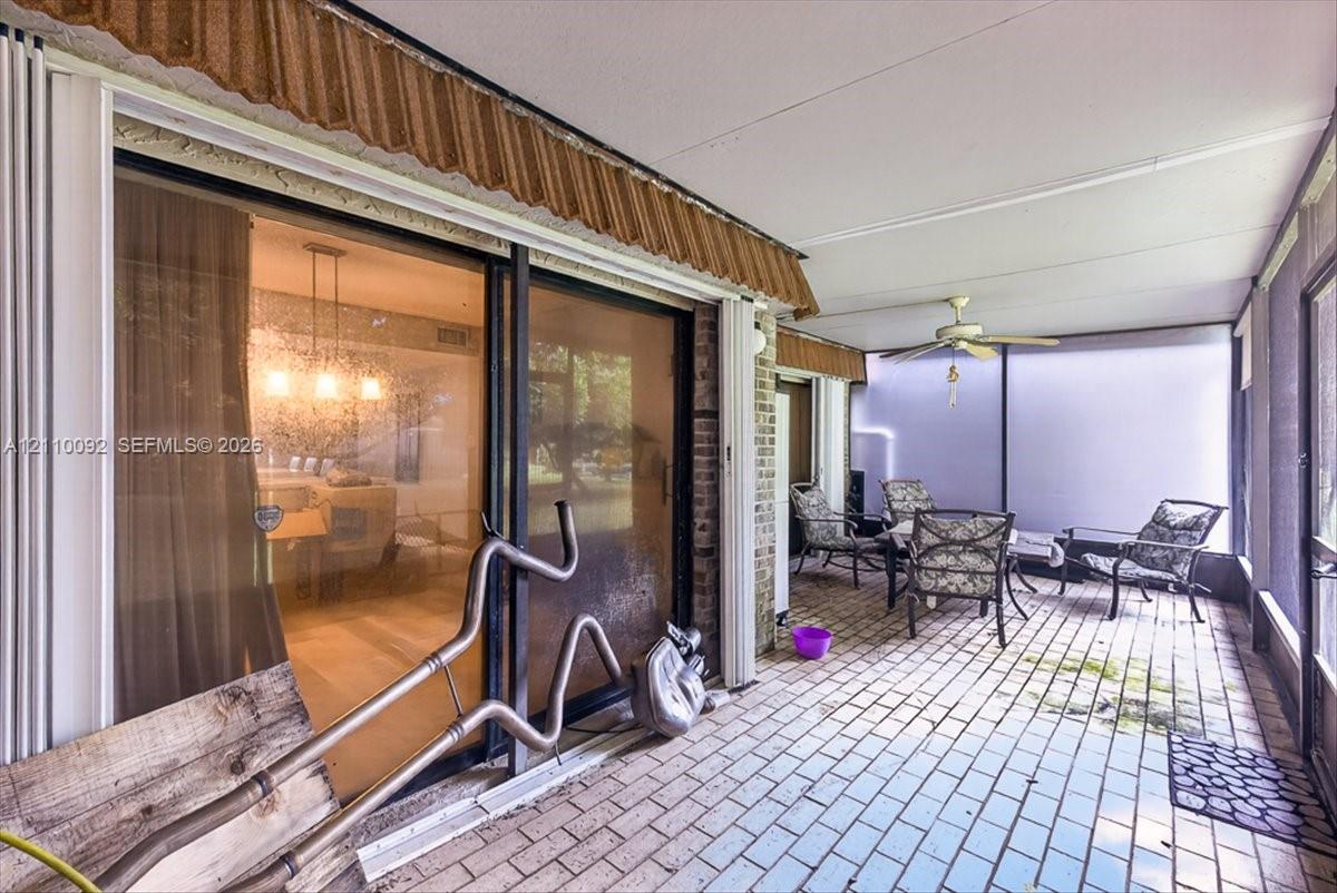 Enclosed patio featuring brick-style flooring, a ceiling fan, and sliding glass door entry
