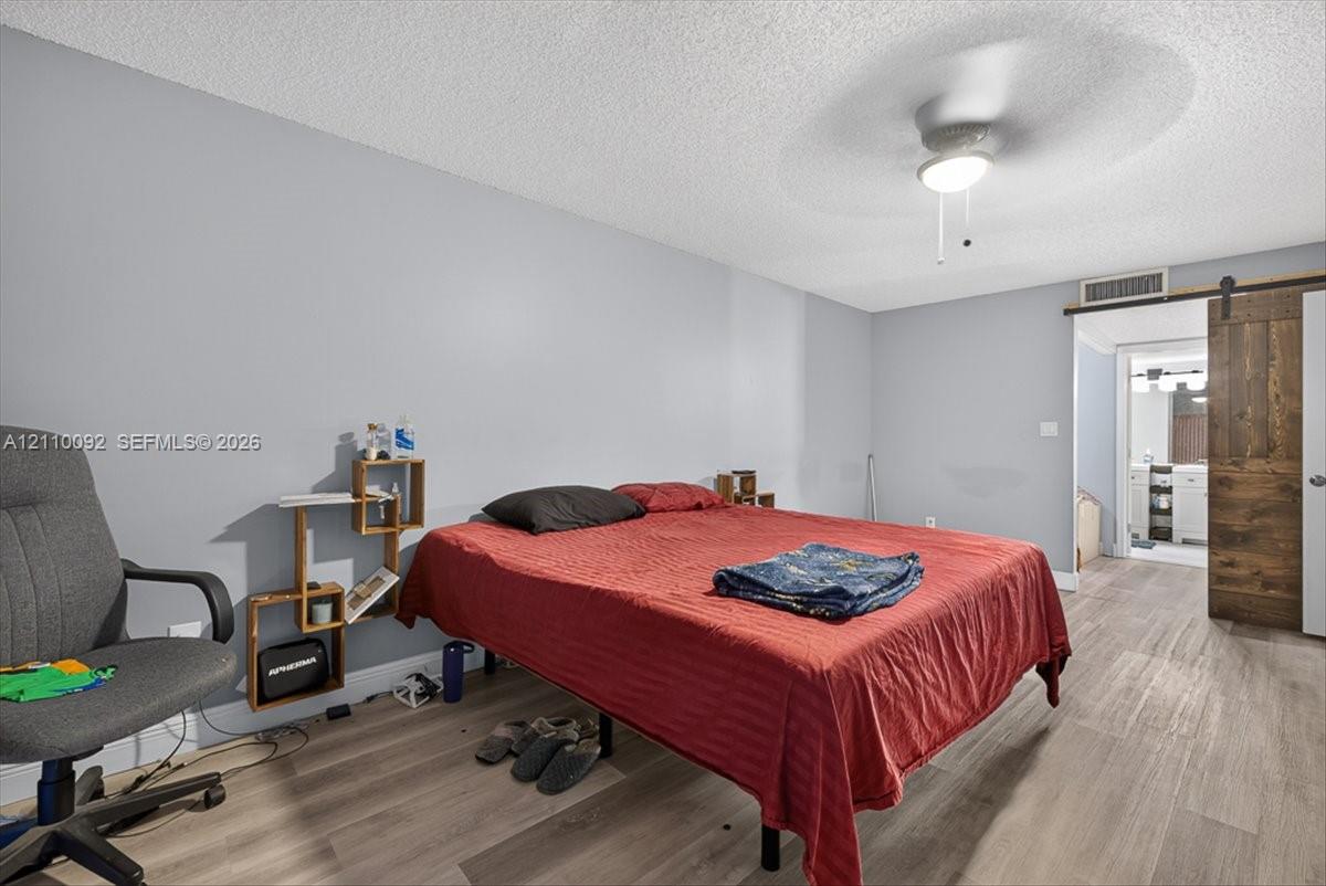 Room featuring wood-finish flooring, a sliding barn-style door, and a ceiling-mounted light fixture