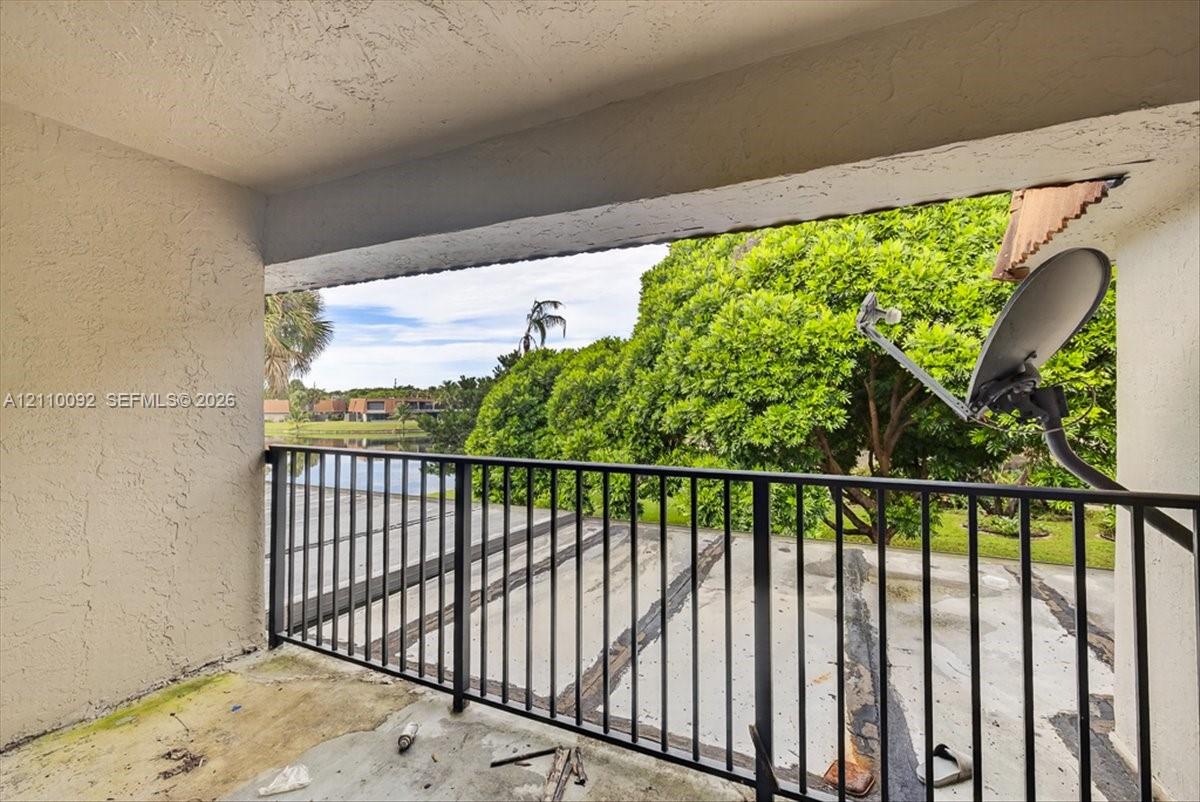 Covered balcony featuring concrete flooring and black metal railing