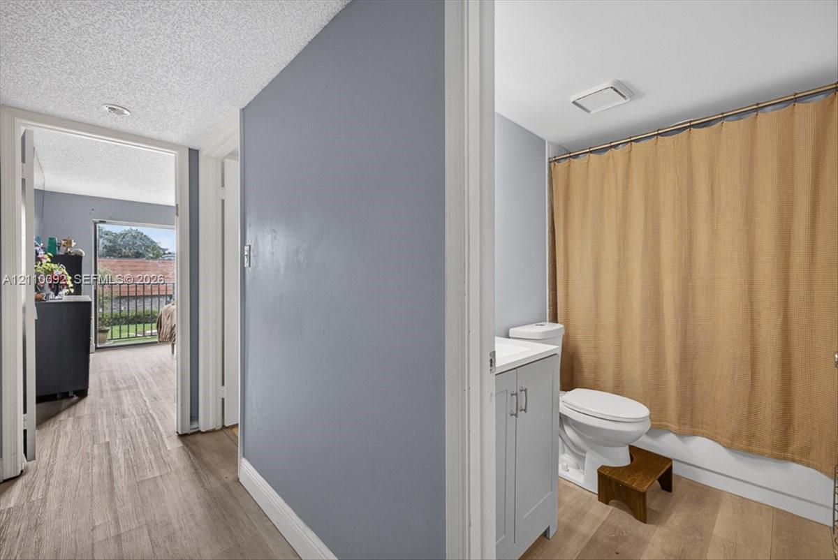 Bathroom featuring a gray vanity cabinet, solid-surface countertop, and wood-finish flooring