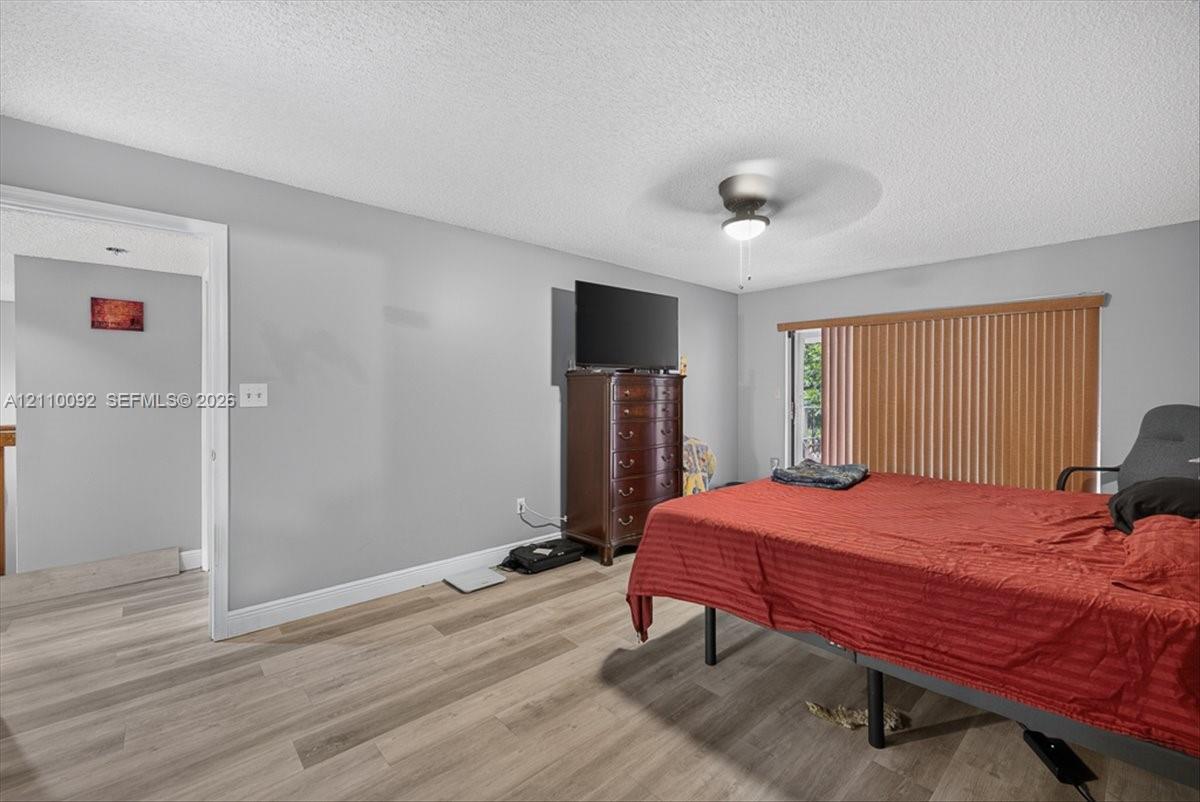 Wood-finish flooring, ceiling fan with integrated lighting, and vertical window blinds
