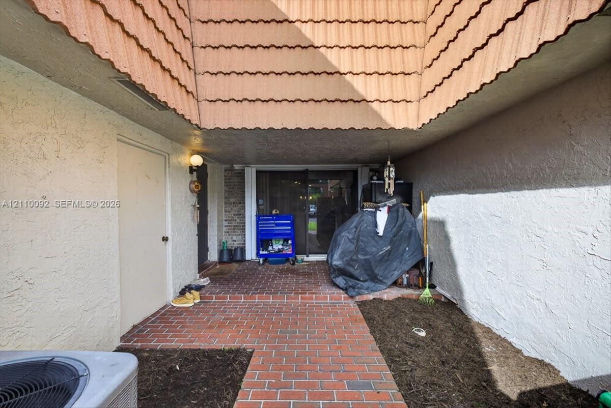 Enclosed courtyard featuring brick flooring, stucco exterior walls, and overhead architectural detailing