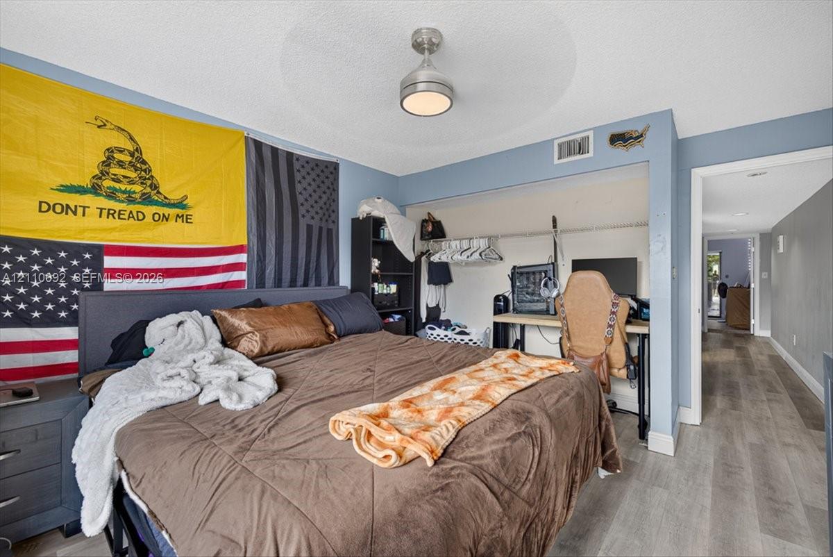 Room featuring wood-finish flooring, a neutral paint palette, and a central brushed-metal ceiling fixture with integrated lighting