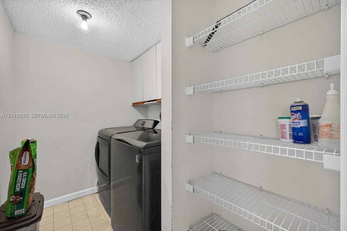 Laundry area featuring white cabinetry, wire shelving, and tiled flooring