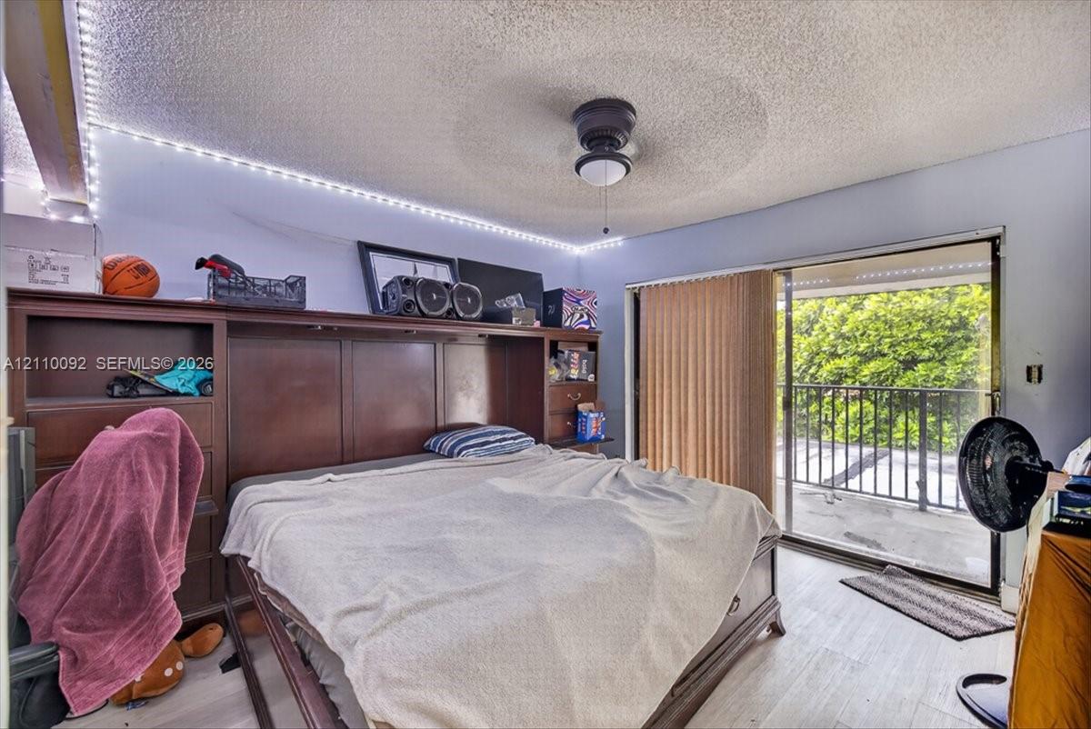 Built-in wood cabinetry, ceiling fan, wood-finish flooring, and sliding glass door leading to a balcony