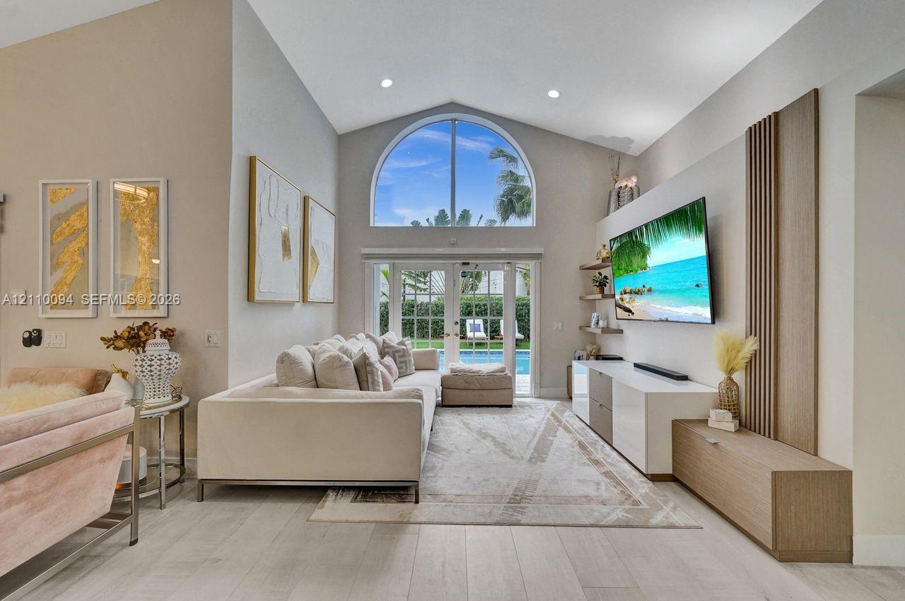 Vaulted ceilings featuring an arched window, wood-finish flooring, custom built-in cabinetry, and recessed lighting