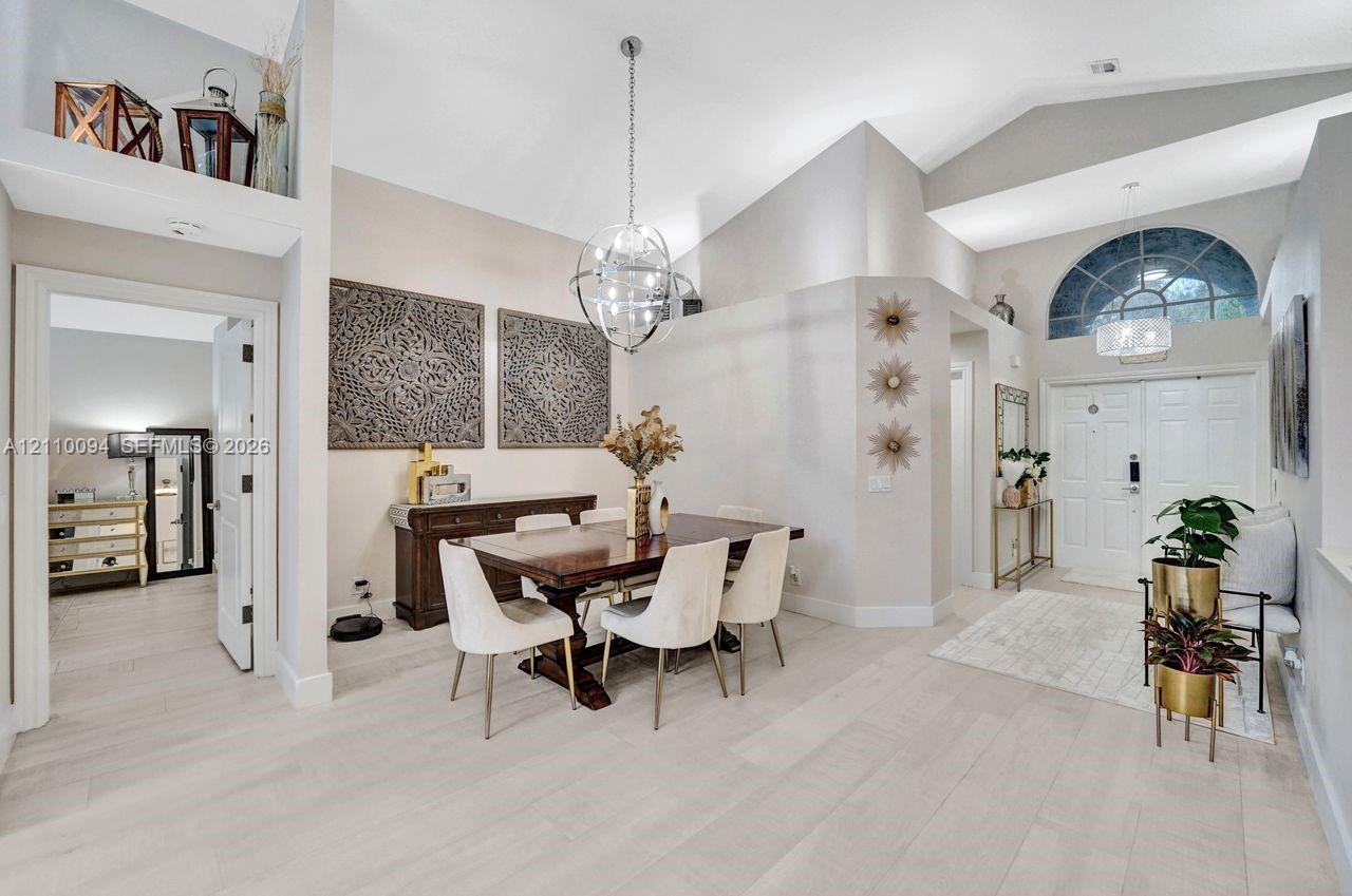 Vaulted ceilings, wood-finish flooring, recessed architectural niche, spherical pendant lighting, and arched transom window