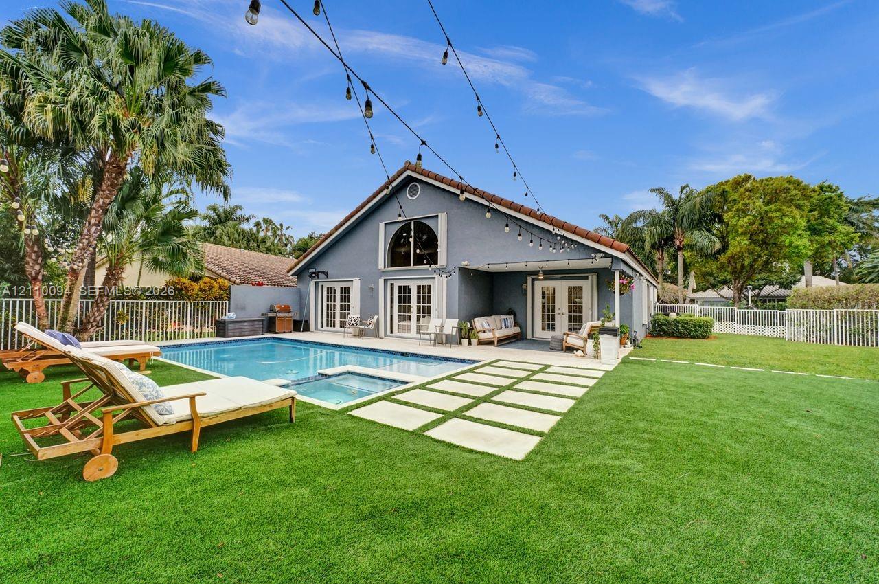 Backyard featuring an in-ground swimming pool with integrated spa, paved stone walkway, covered patio, and perimeter fencing