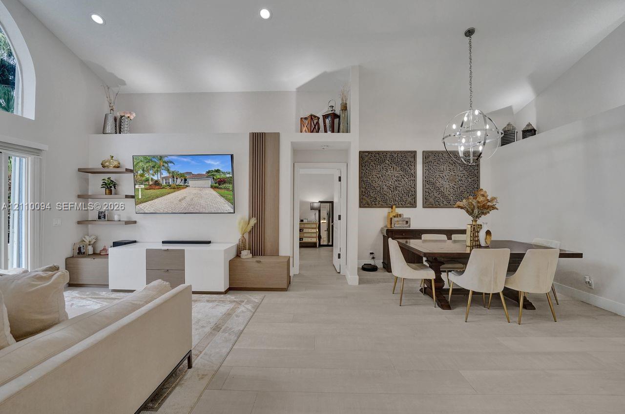 Vaulted ceilings, custom wall-mounted shelving, integrated vertical wood-slat accent paneling, recessed lighting, and a modern spherical chandelier