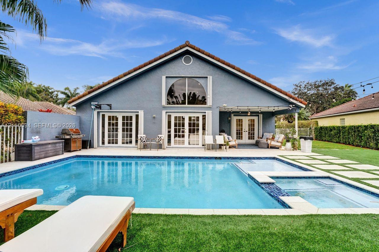 Backyard featuring an in-ground swimming pool, attached spa, covered patio, multiple sets of French doors, and a manicured lawn Backyard featuring an in-ground swimming pool, attached spa, covered patio, multiple sets of French doors, and a manicured lawn