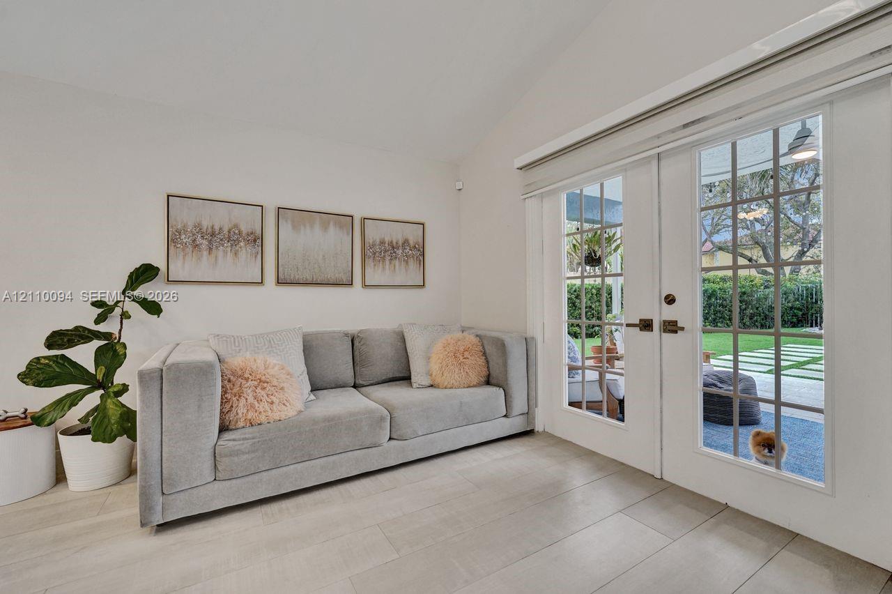 Vaulted ceiling, neutral tile flooring, and multi-lite French doors
