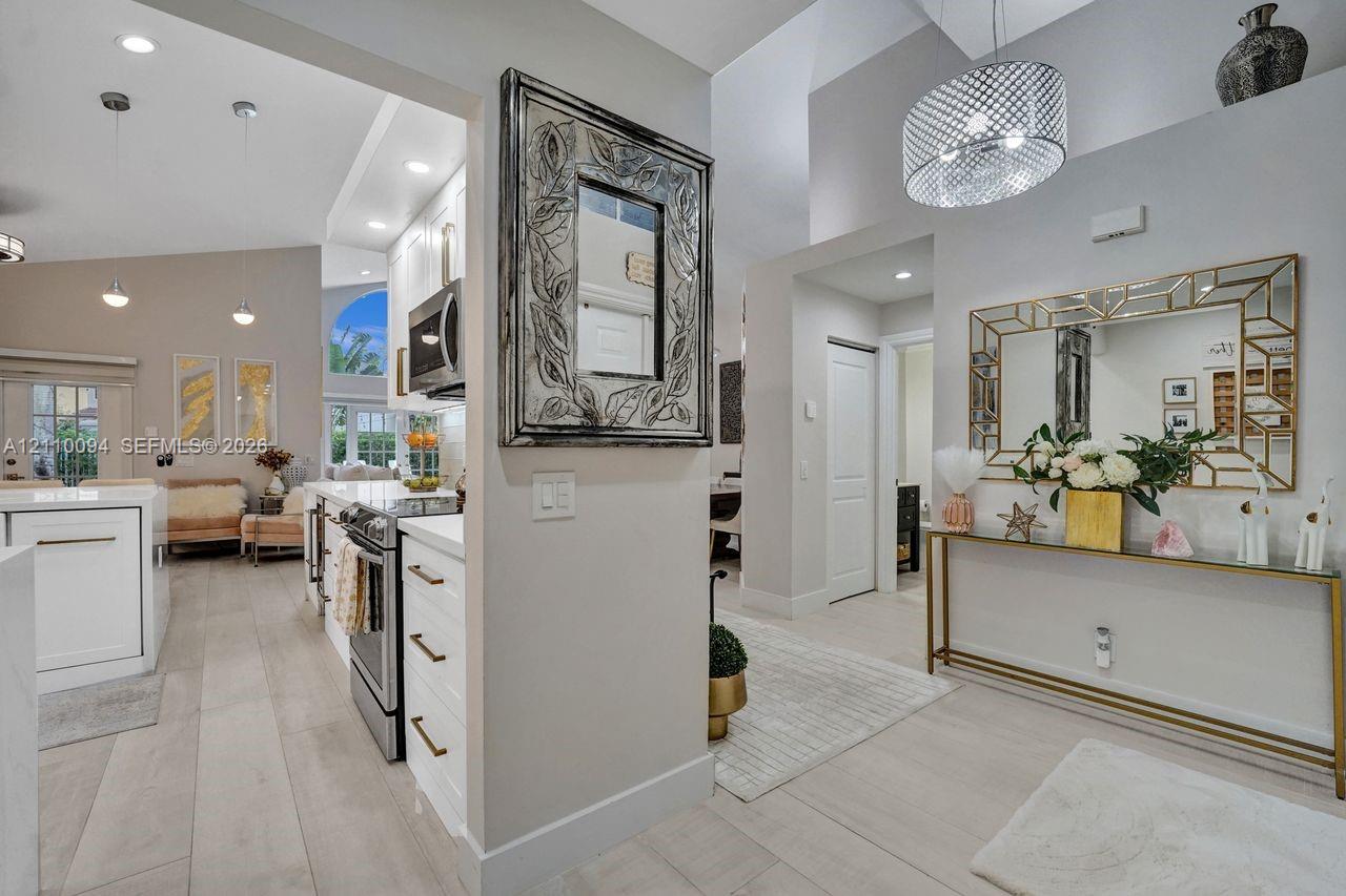 Vaulted ceilings, wood-finish flooring, white shaker-style cabinetry, stainless steel appliances, and decorative recessed and pendant lighting