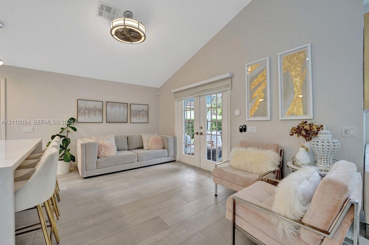 Vaulted ceiling, wood-finish flooring, and glass-paneled double doors leading to the exterior