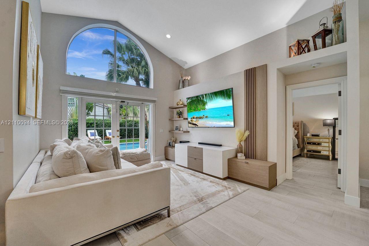 Vaulted ceiling, arched window, wood-finish flooring, built-in cabinetry, and French doors