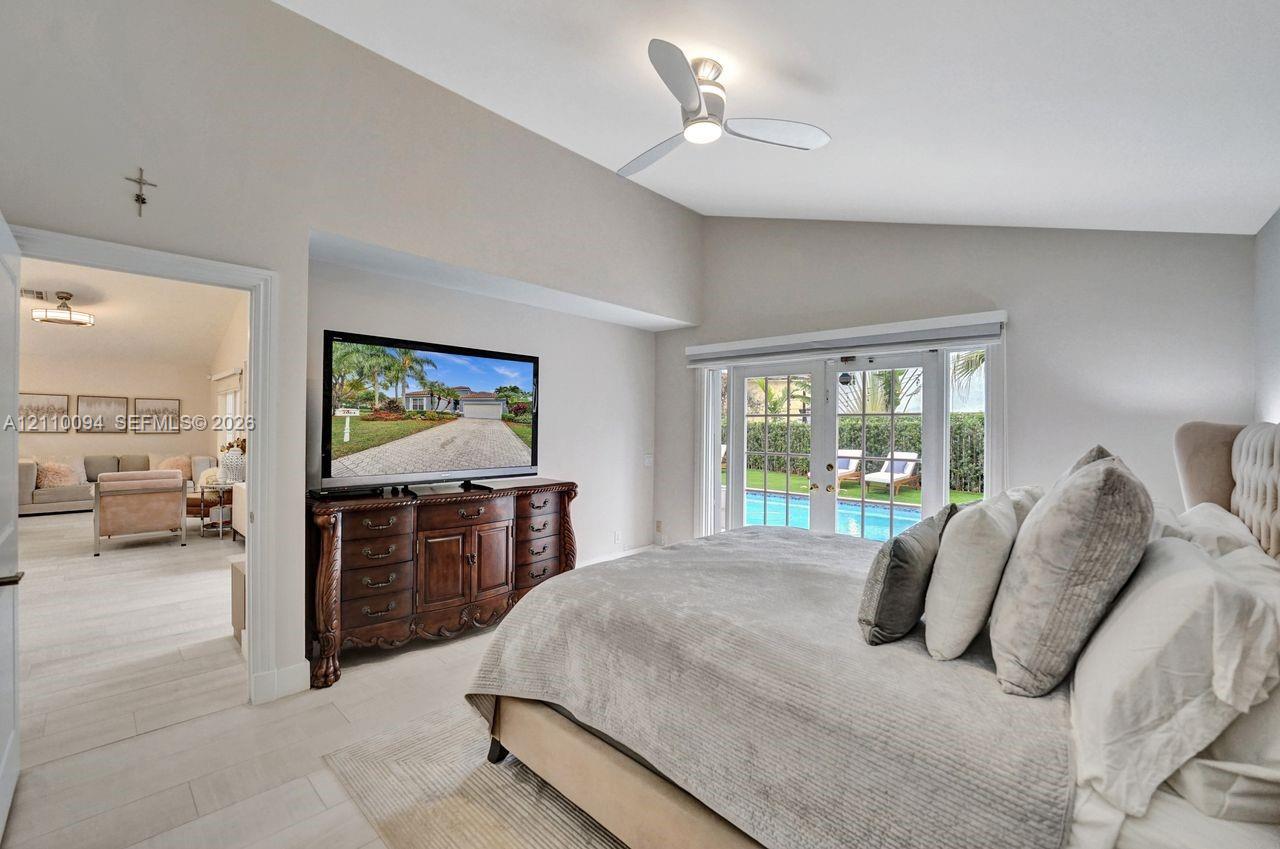 Vaulted ceilings, neutral paint, light-toned flooring, integrated ceiling fan with light fixture, and French doors featuring exterior pool access