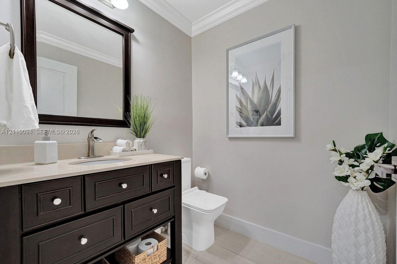 Dark-finish vanity featuring an integrated basin and light-toned countertop, framed wall mirror, and crown molding