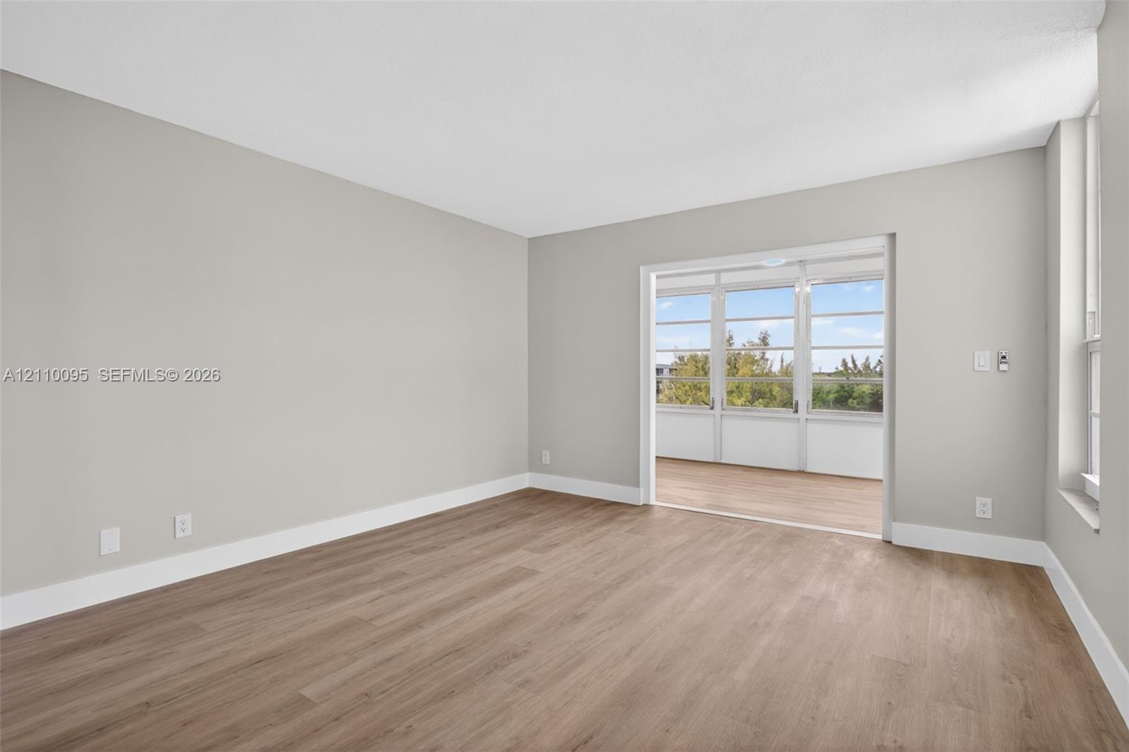 Neutral wall paint, wood-finish flooring, and large glass-paneled doors opening to an enclosed outdoor space