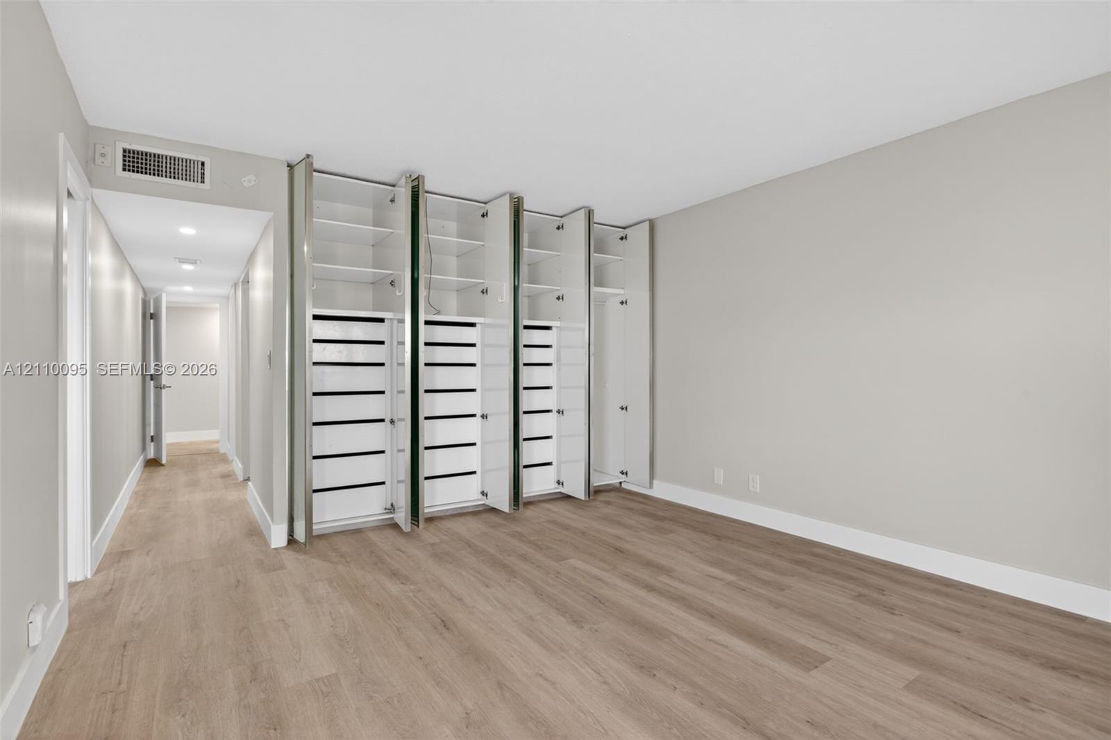 Room featuring wood-finish flooring, recessed ceiling lighting, and floor-to-ceiling built-in cabinetry with integrated shelving and drawer storage