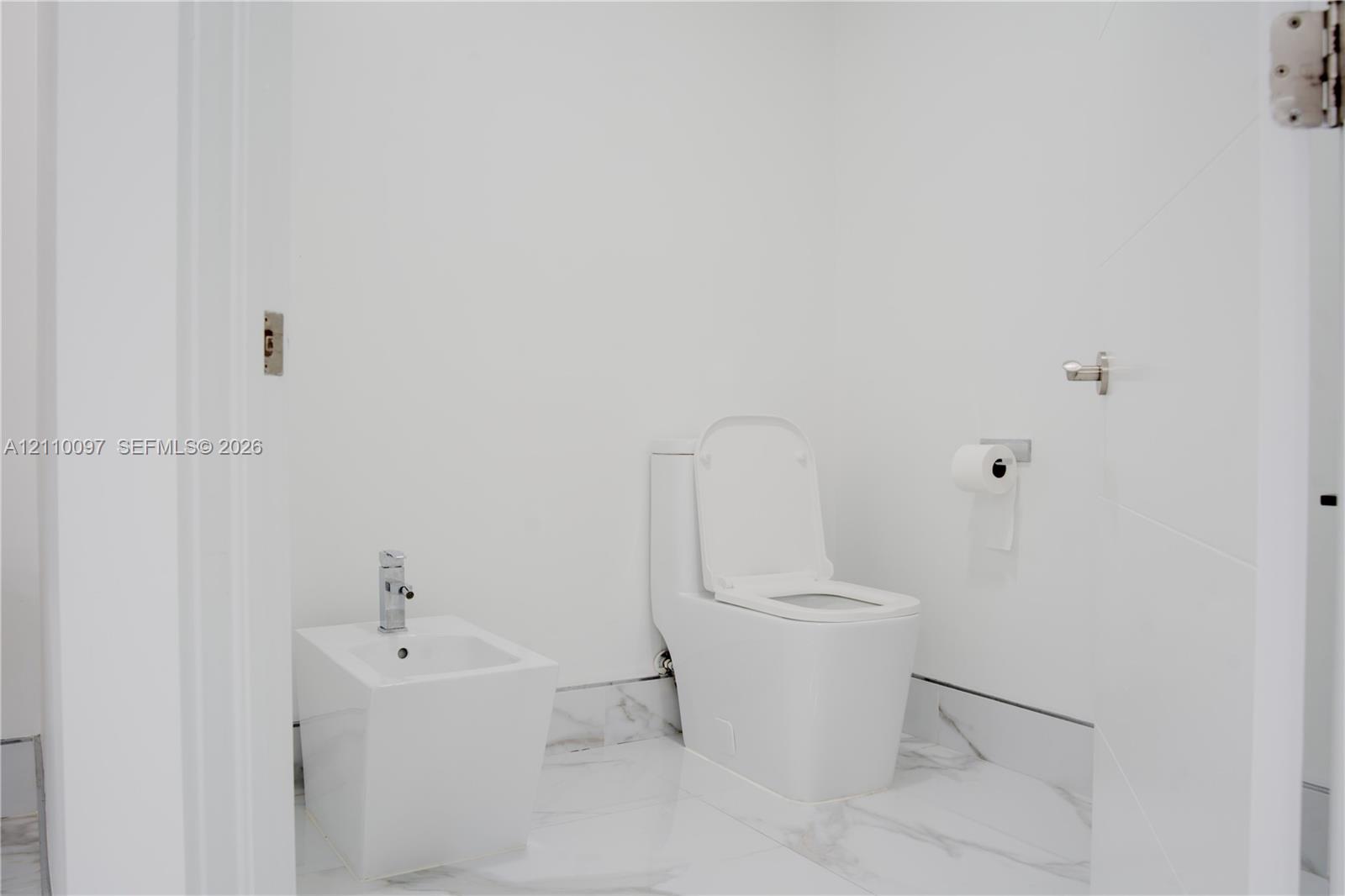 Freestanding soaking tub with a wall-mounted chrome hand shower and faucet assembly, accented by a decorative navy and white geometric tiled wall