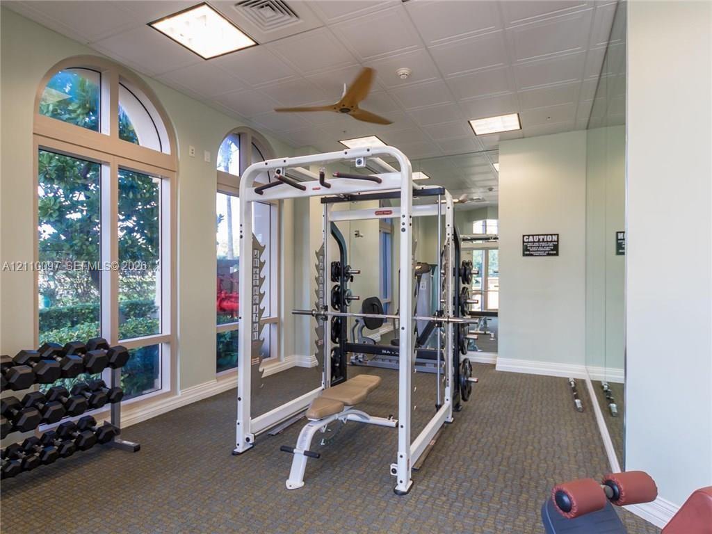 Fitness space featuring tall arched windows, full-wall mirrors, recessed lighting, and a ceiling fan