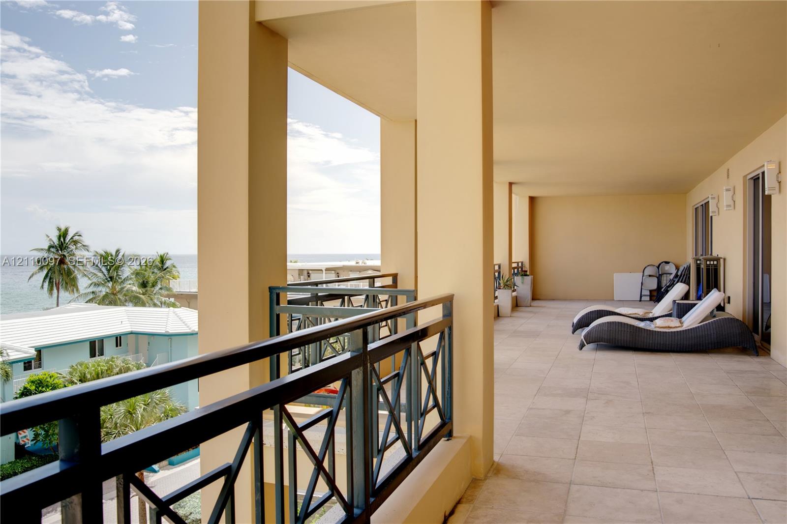 Expansive covered terrace featuring stone tile flooring, structural columns, and a geometric metal railing