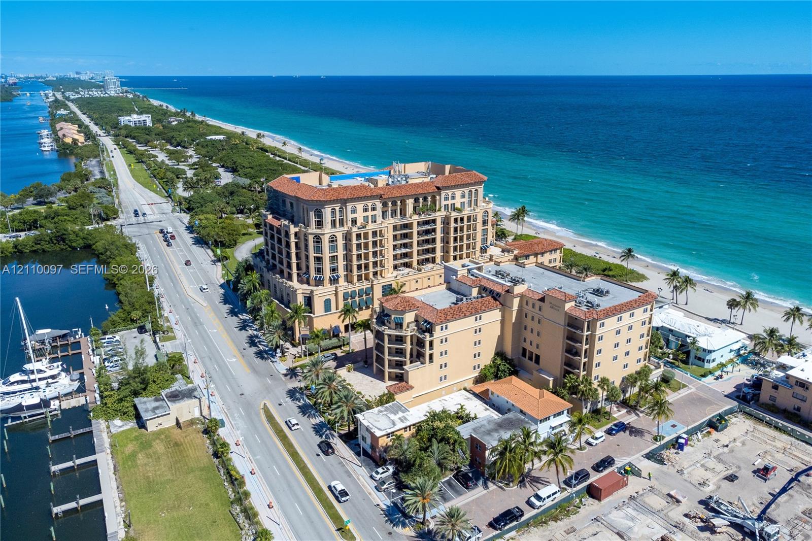 Multi-story masonry building with terracotta tile roof, recessed balconies, and direct proximity to the ocean and coastline Multi-story masonry building with terracotta tile roof, recessed balconies, and direct proximity to the ocean and coastline