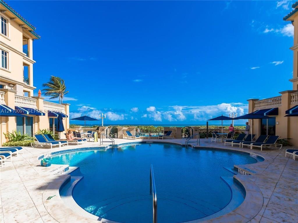 Outdoor swimming pool featuring stone deck surround, integrated perimeter railing, and masonry building exterior