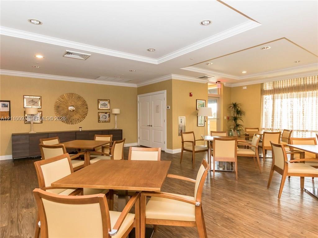 Common area featuring wood-finish flooring, recessed lighting, crown molding, double-panel doors, and large windows with integrated blinds