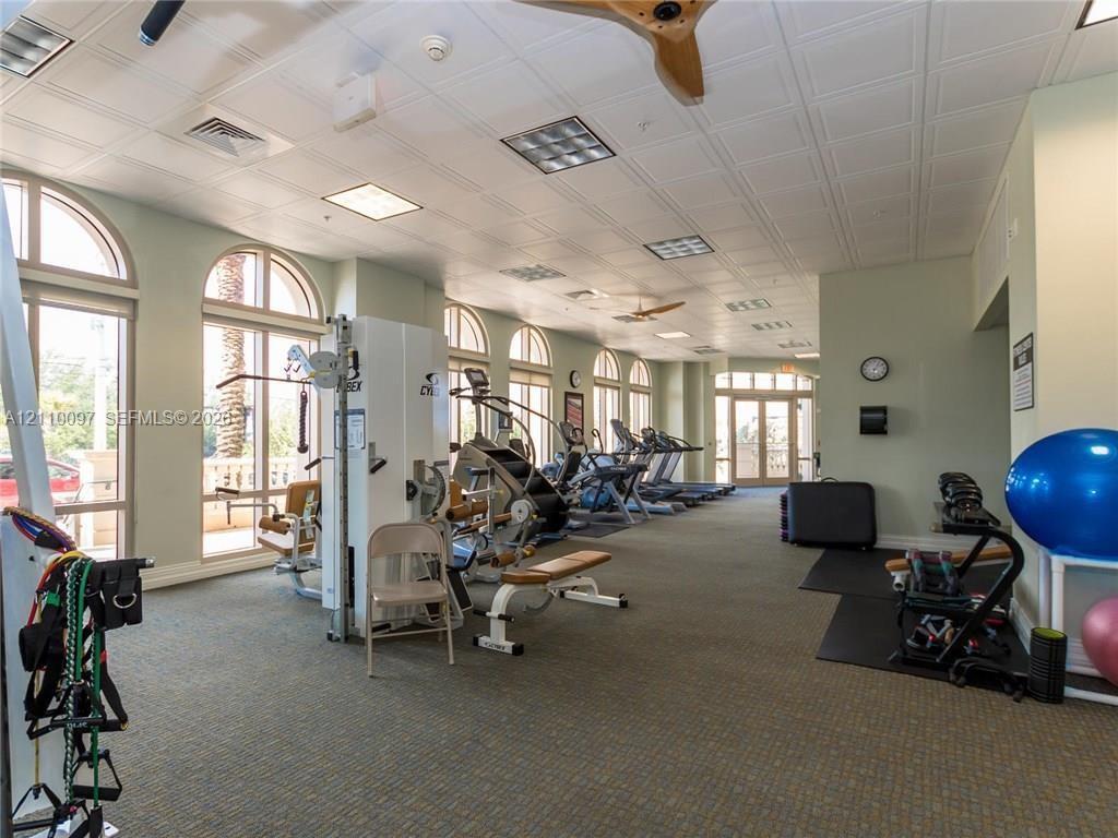 Fitness center featuring arched windows, paneled ceiling, recessed lighting, and integrated ceiling fans