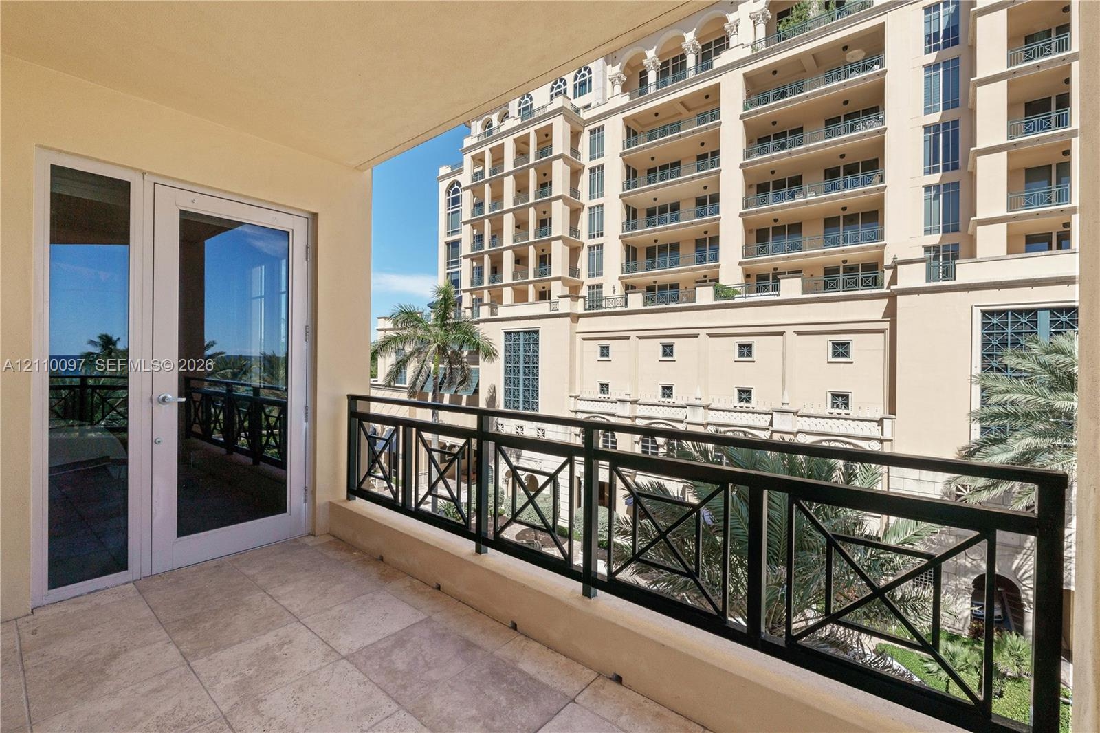 Covered balcony featuring stone tile flooring and a black metal geometric railing