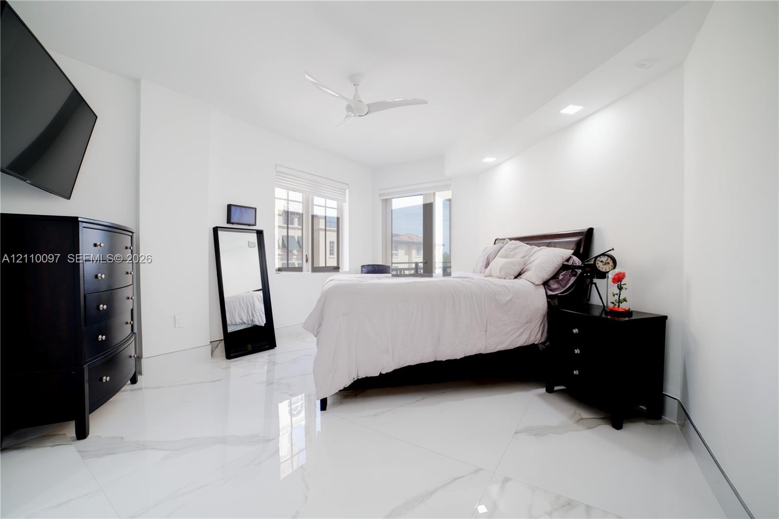 Large-format stone tile flooring, recessed ceiling lighting, and a white multi-blade ceiling fan
