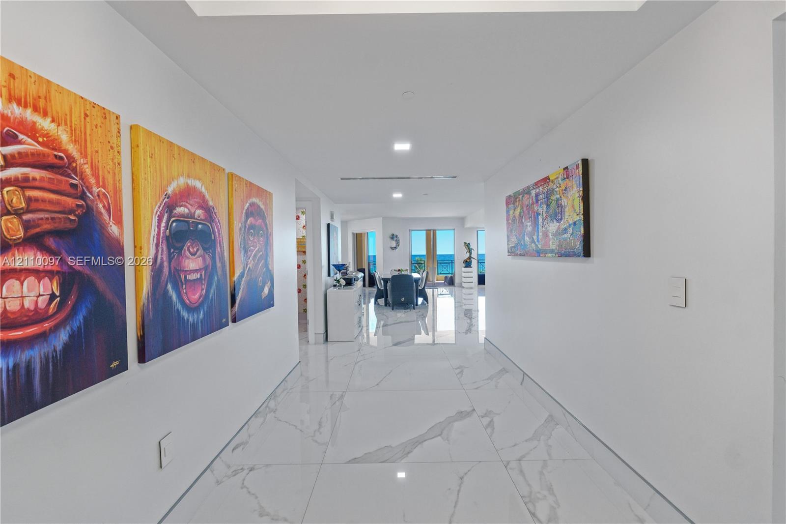 Large-format stone-finish floor tiling, recessed ceiling lighting, and expansive glass doors offering ocean exposure