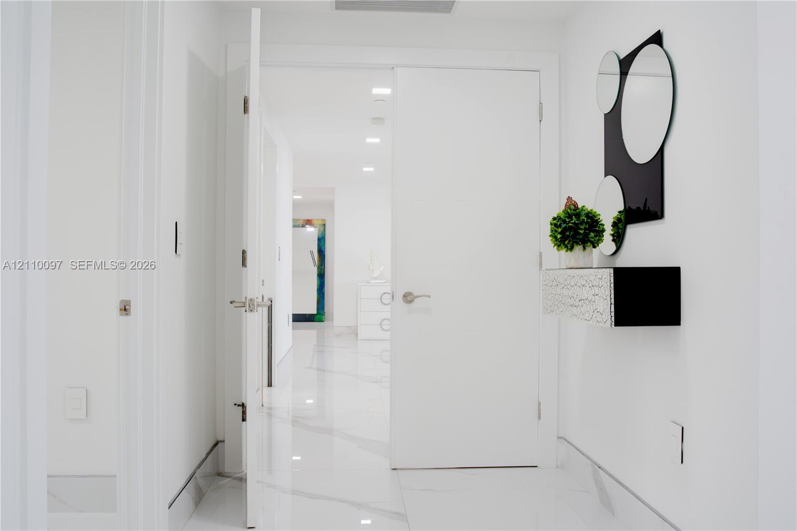 Interior hallway featuring large-format white veined flooring and recessed ceiling lighting