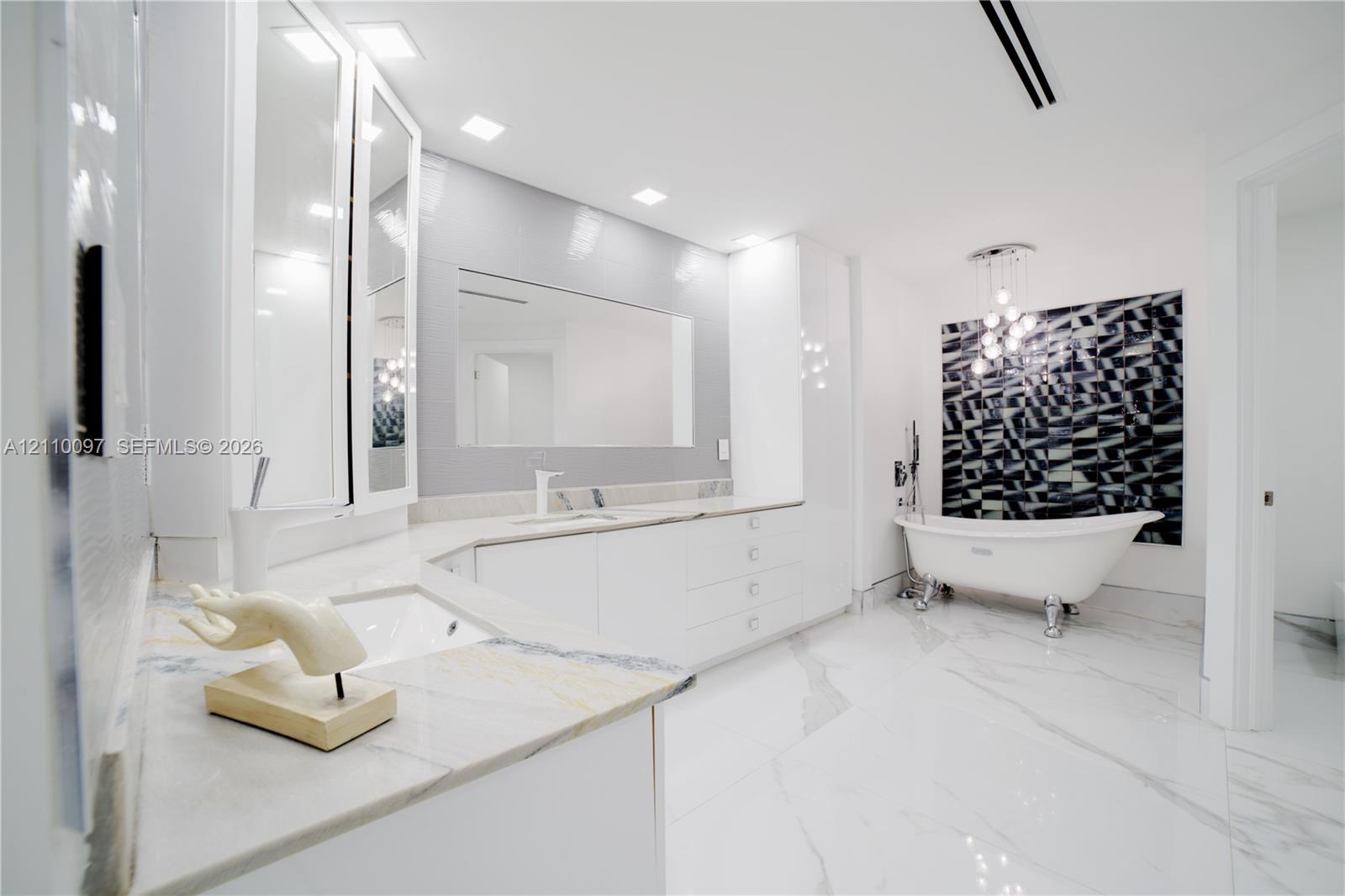 Bathroom featuring a white clawfoot tub, custom built-in cabinetry with stone countertops, large-format tile flooring, recessed ceiling lighting, and a multi-pendant light fixture