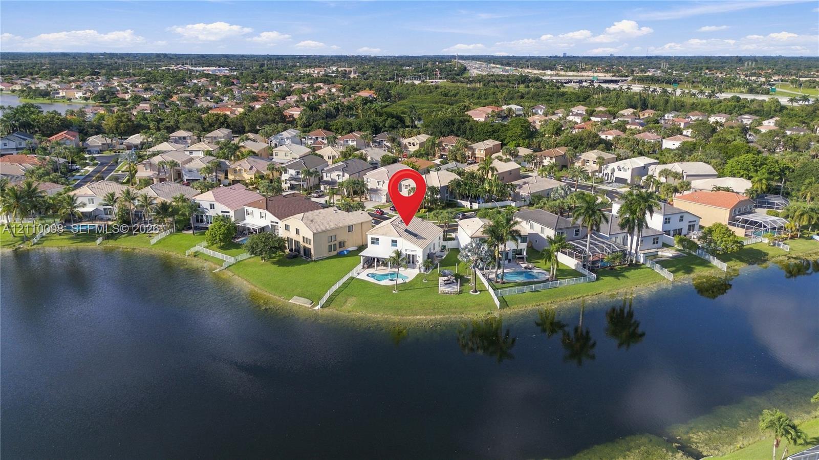 Waterfront property featuring a private swimming pool, expansive rear lawn, and mature palm trees