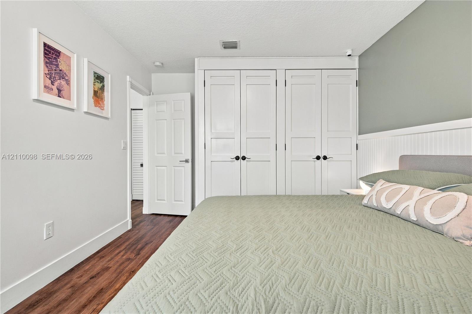 Wood-finish flooring, built-in floor-to-ceiling cabinetry with shaker-style doors, and decorative beadboard wainscoting