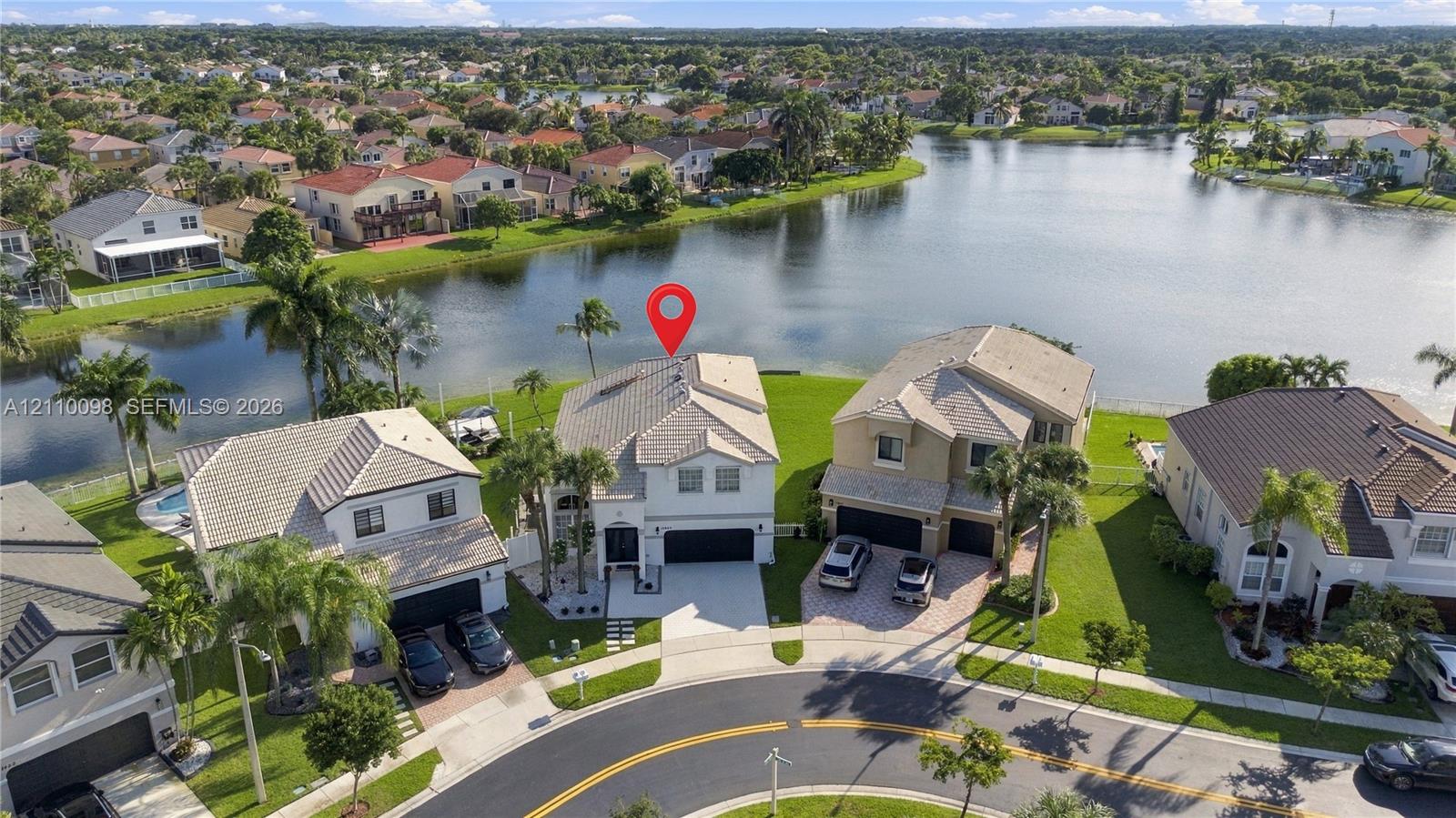Waterfront property featuring a tile roof, two-car garage, and a paver driveway