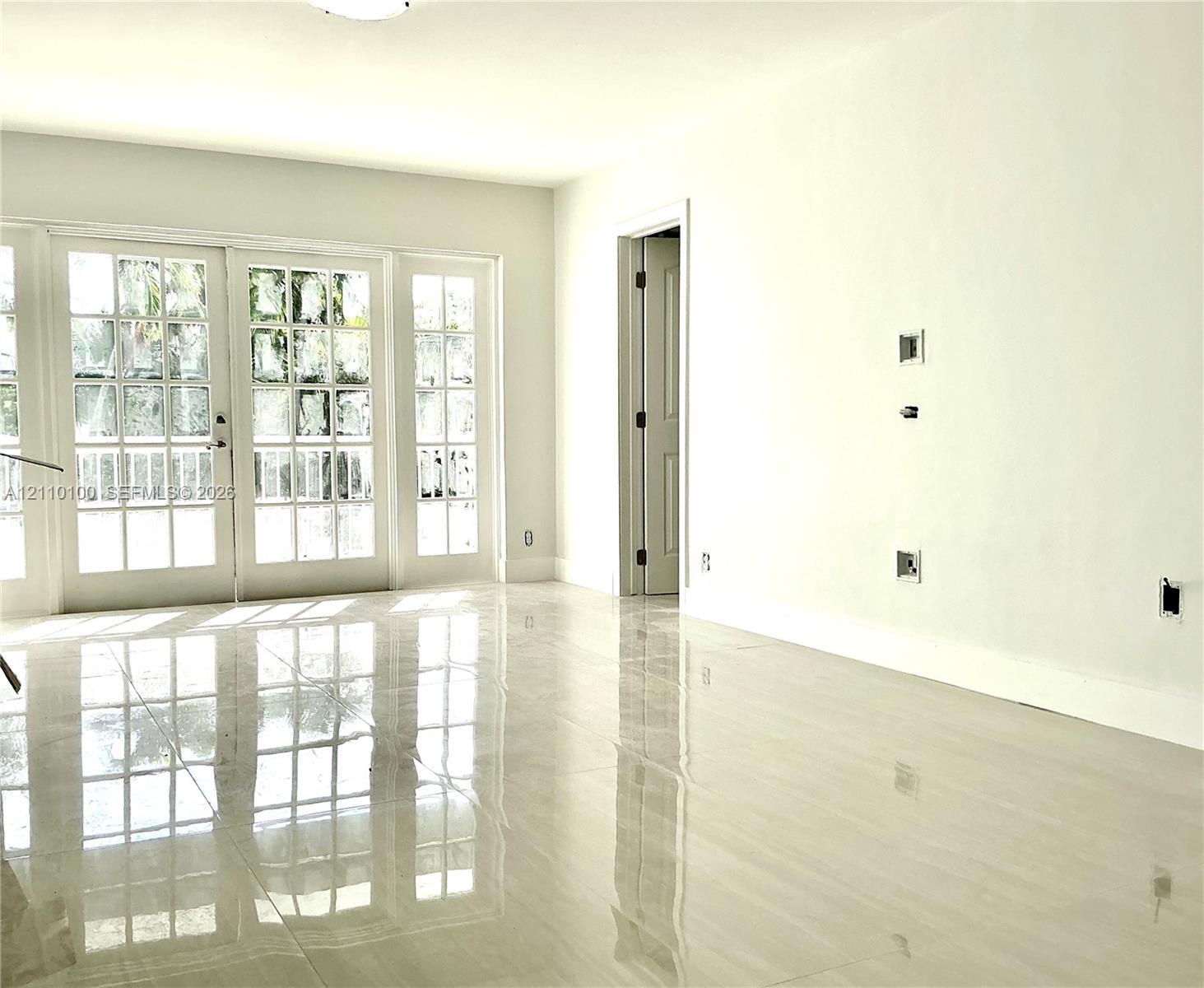 Polished neutral-tone tile flooring, multi-pane glass French doors, and smooth wall finish Polished neutral-tone tile flooring, multi-pane glass French doors, and smooth wall finish