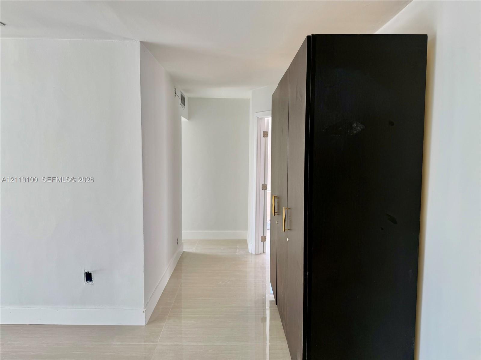 Neutral-toned tile flooring throughout with built-in, full-height dark cabinetry featuring metallic pulls and smooth walls