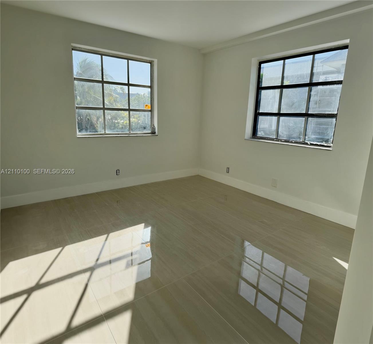 Room interior featuring large-format polished tile flooring, neutral wall tones, and two windows with multi-pane grid detailing Room interior featuring large-format polished tile flooring, neutral wall tones, and two windows with multi-pane grid detailing