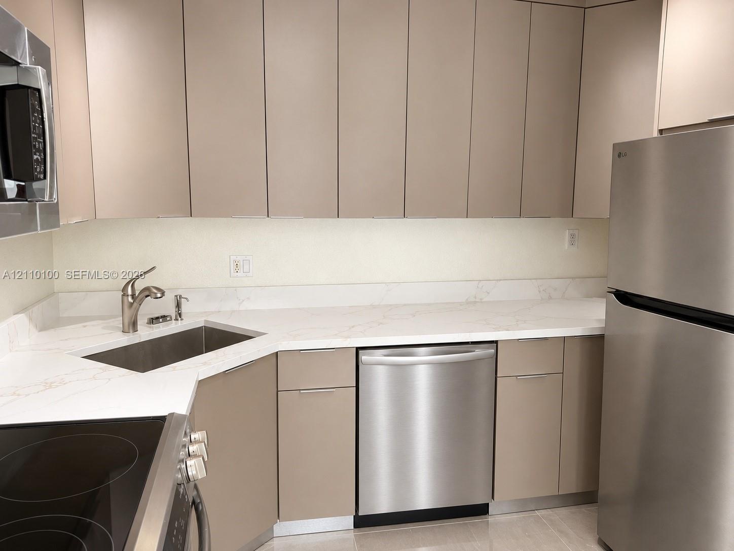 Kitchen featuring slab-style cabinetry, stone-finish countertops, stainless steel appliances, and a undermount sink with a gooseneck faucet Kitchen featuring slab-style cabinetry, stone-finish countertops, stainless steel appliances, and a undermount sink with a gooseneck faucet