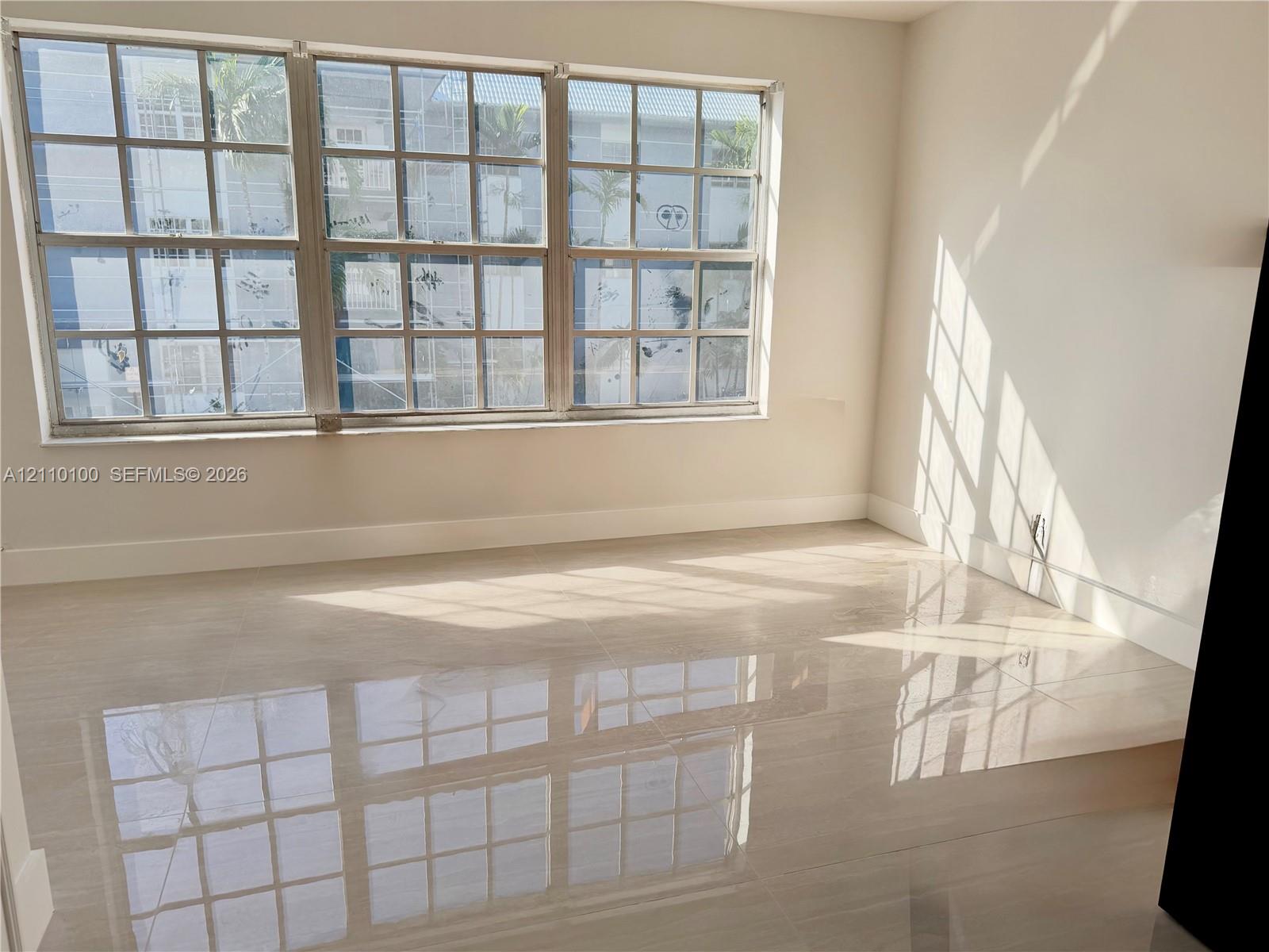 Large grid-pattern windows, neutral wall paint, and polished stone-finish tile flooring Large grid-pattern windows, neutral wall paint, and polished stone-finish tile flooring
