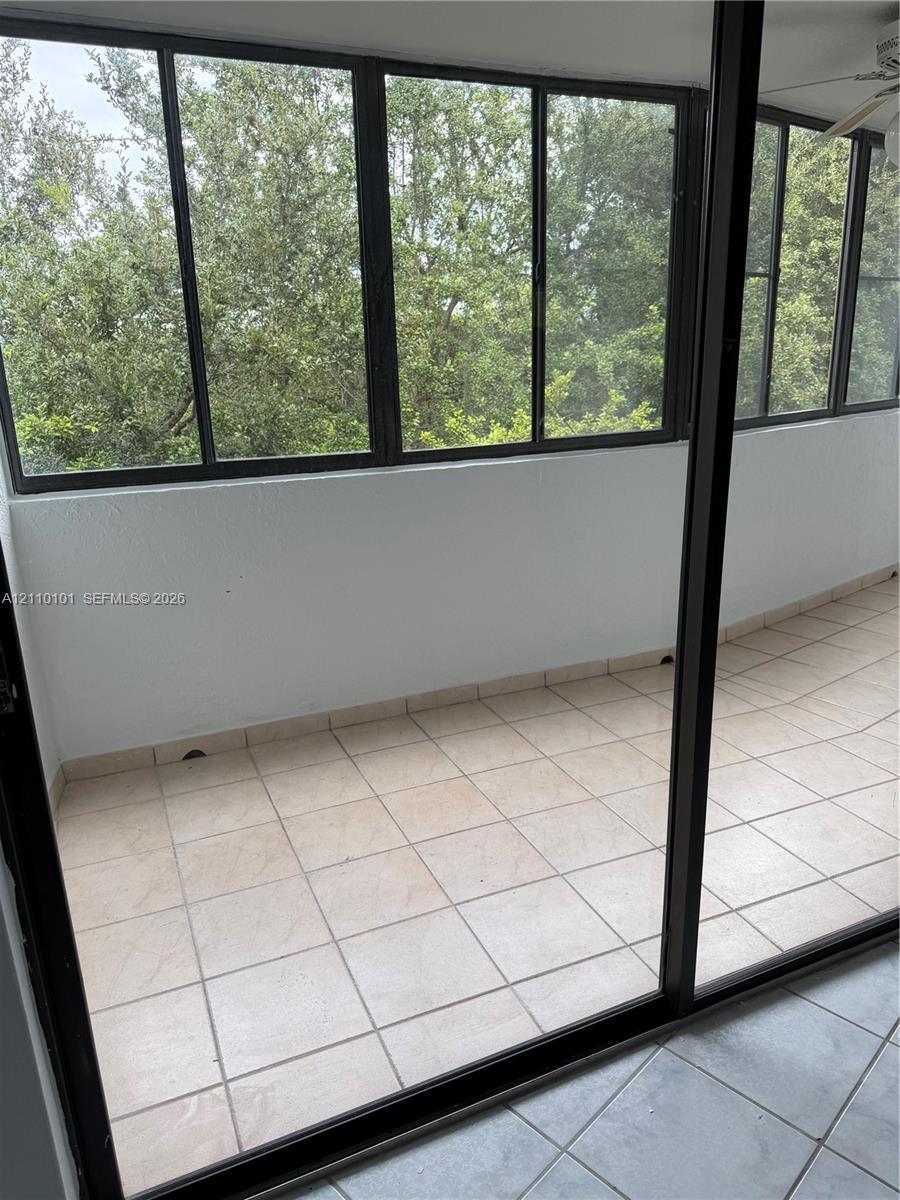 Enclosed porch featuring tile flooring, expansive window panels, and a ceiling fan