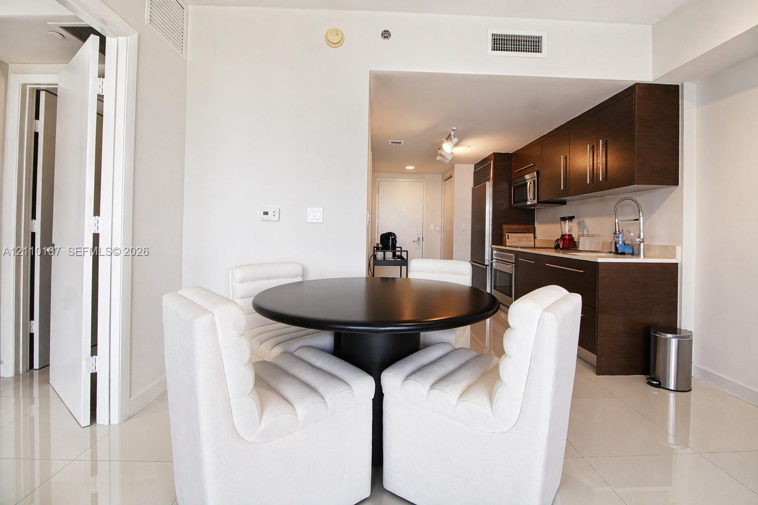 Kitchen featuring dark wood-finish cabinetry, stainless steel appliances, and a gooseneck faucet, finished with polished tile flooring throughout