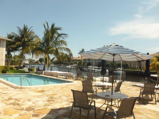 Waterfront patio featuring natural stone hardscaping, an in-ground swimming pool, and direct canal access