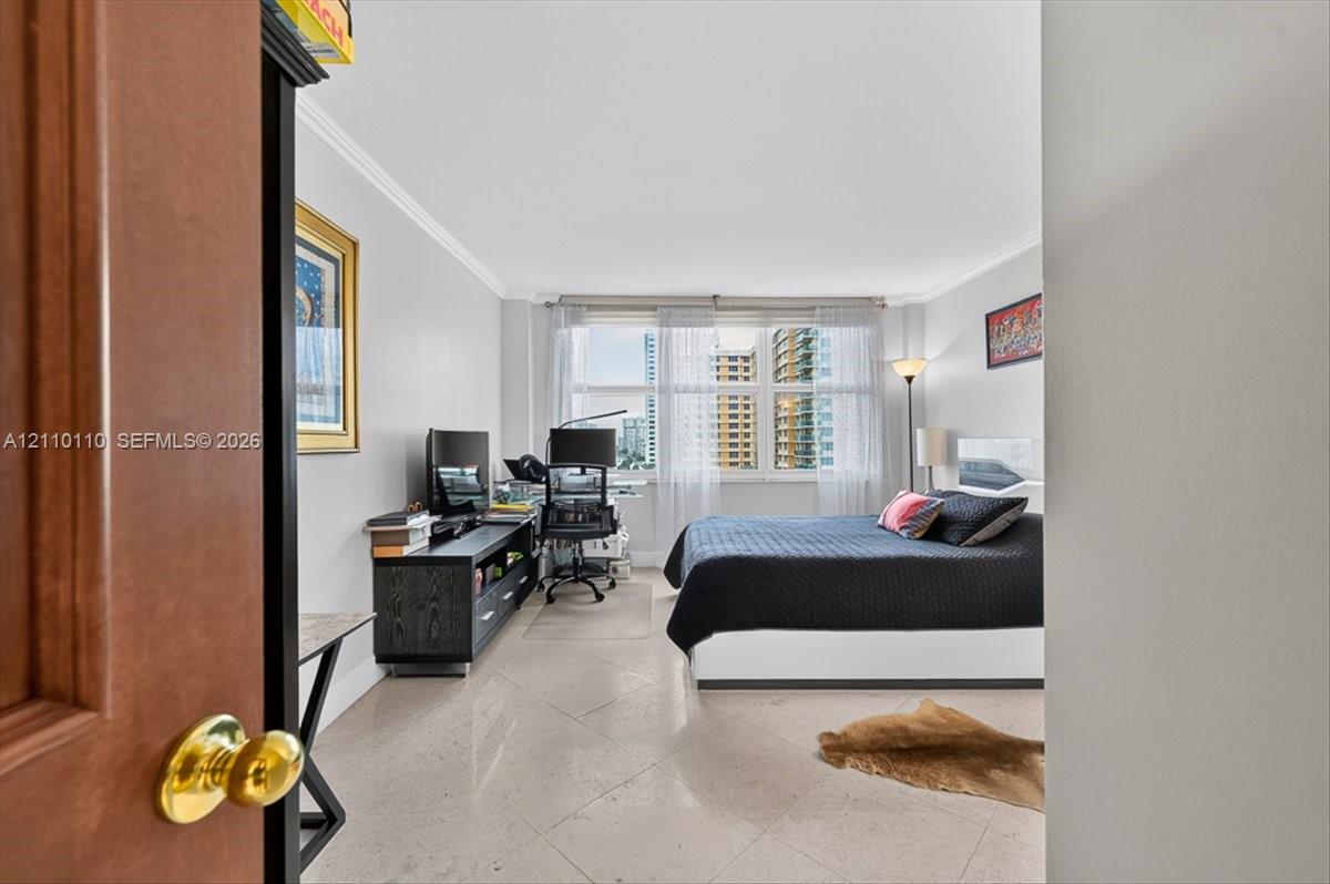 Room featuring large-format diagonal tile flooring, crown molding, and expansive multi-panel windows