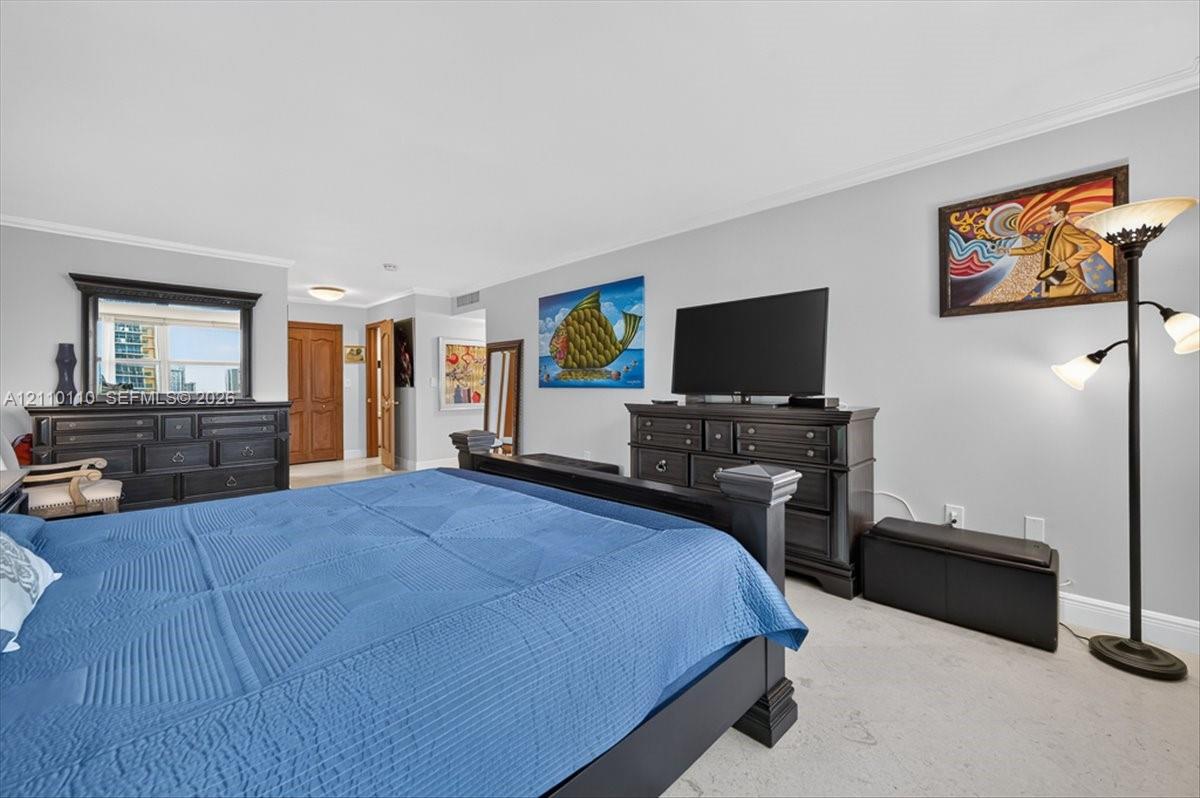 Neutral-toned walls, crown molding, light-colored carpeting, and natural light via the window