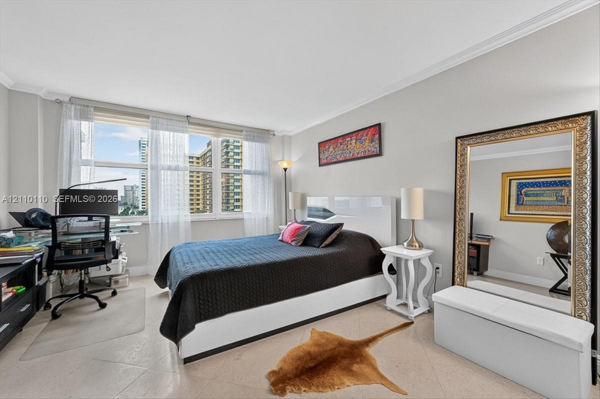 Room featuring large windows with multi-pane glazing, light-toned stone-finish flooring, and crown molding