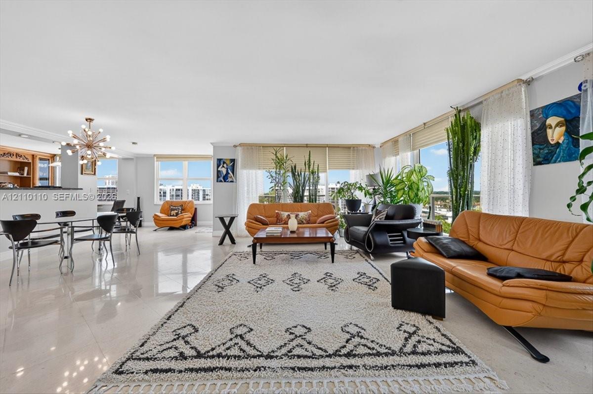 Open-concept interior featuring large-format tile flooring, floor-to-ceiling windows, built-in cabinetry, and a modern sputnik-style chandelier