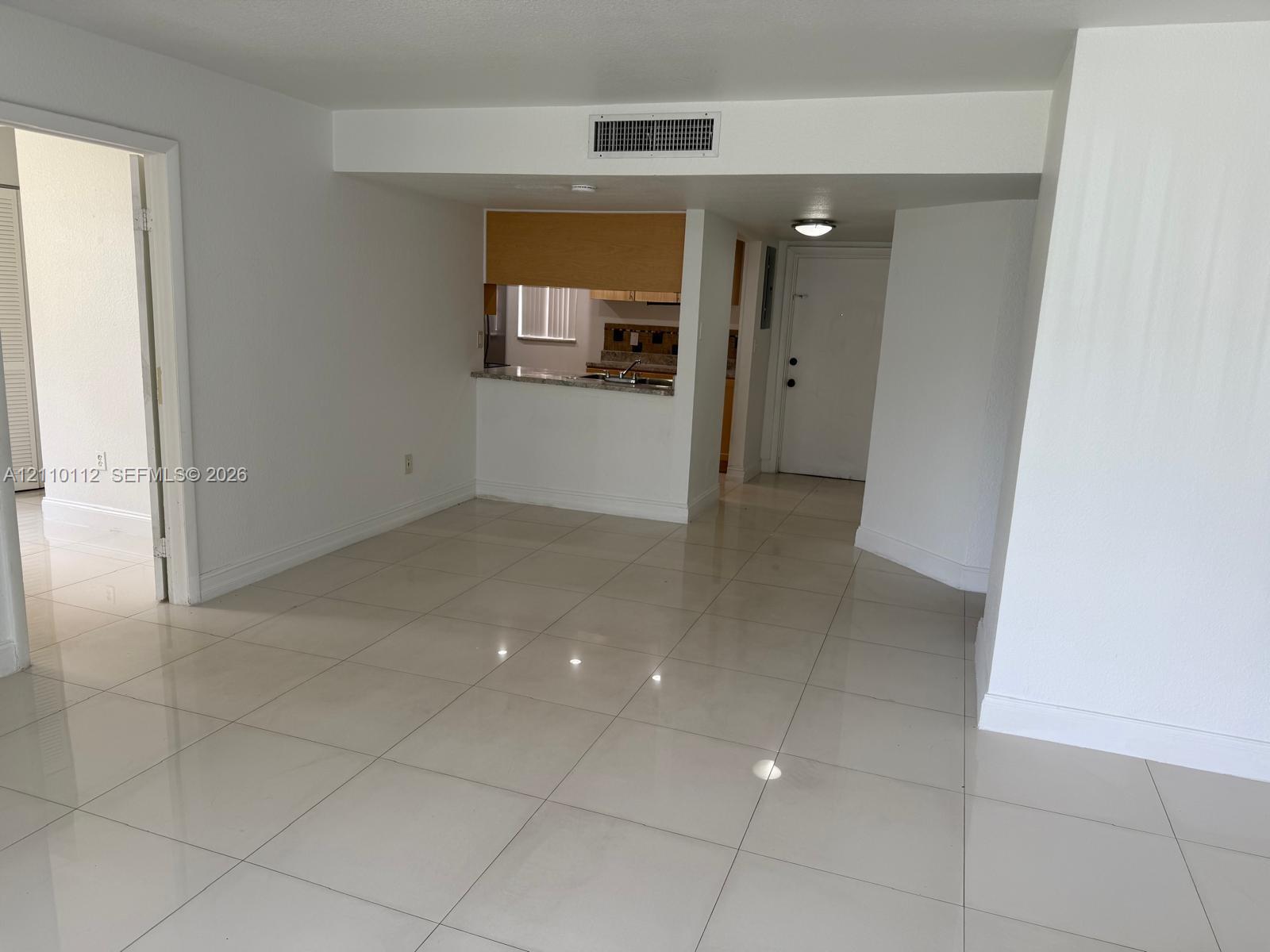 Polished tile flooring, kitchen pass-through window, and neutral wall finishes